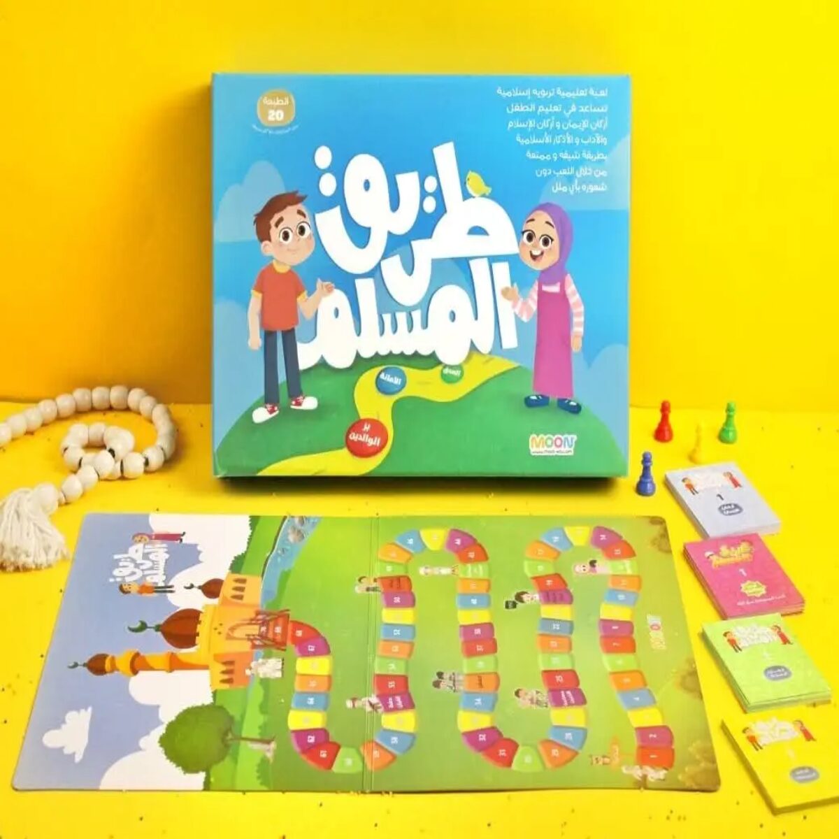 "لعبة طريق المسلم التعليمية للأطفال من إنتاج MOON، تشمل لوحة لعب كرتونية ملونة وكروت أسئلة في العقيدة والآداب، مناسبة للأعمار من 7 إلى 14 سنة."